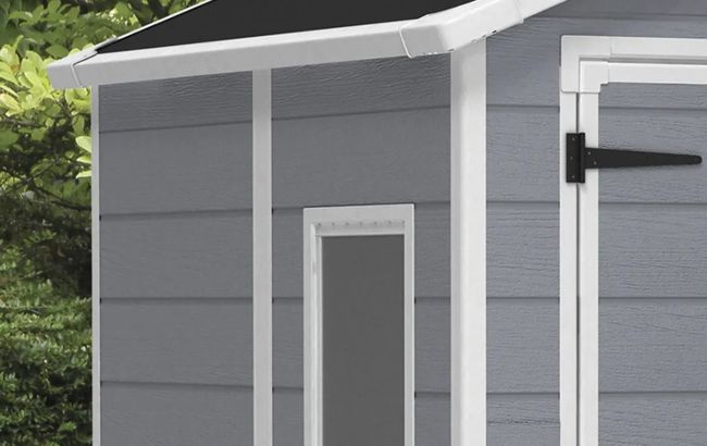 Gray outdoor storage shed with a black roof and white door handle.