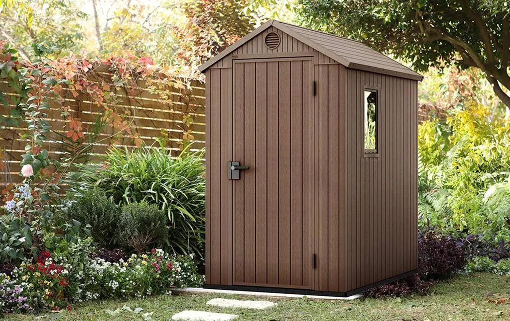 Brown storage shed in a garden setting with plants and flowers around
