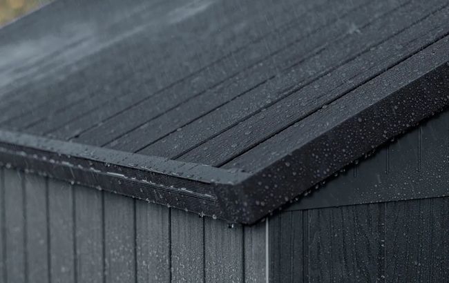 Close-up of a dark gray roof with raindrops on a cloudy day